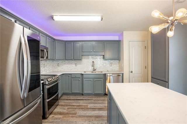 kitchen featuring sink, appliances with stainless steel finishes, hanging light fixtures, dark hardwood / wood-style floors, and decorative backsplash