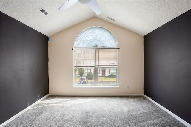 empty room featuring ceiling fan, lofted ceiling, carpet floors, and a textured ceiling