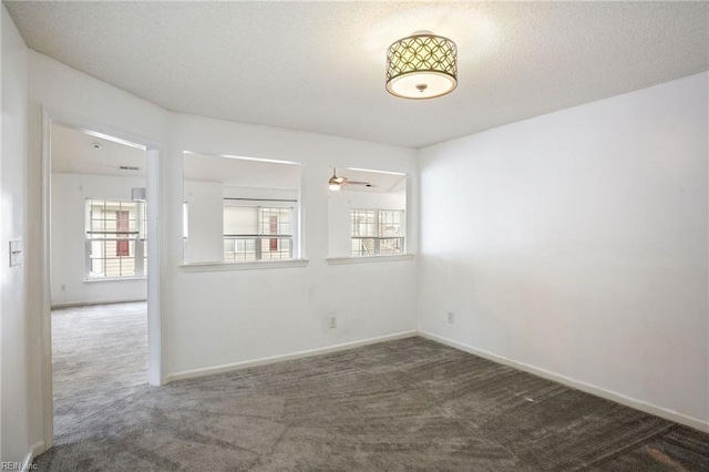 empty room featuring a textured ceiling and dark colored carpet