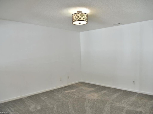 empty room featuring dark carpet and a textured ceiling