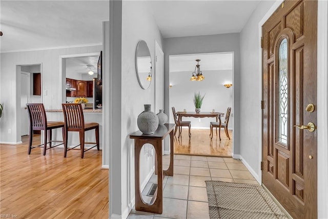 entryway with light tile patterned flooring and crown molding