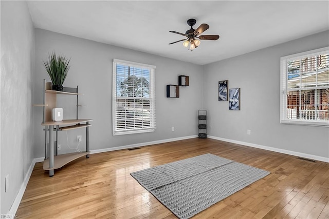 exercise area with ceiling fan, wood-type flooring, and a wealth of natural light