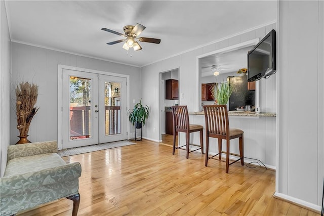 living area featuring crown molding, light hardwood / wood-style floors, and french doors