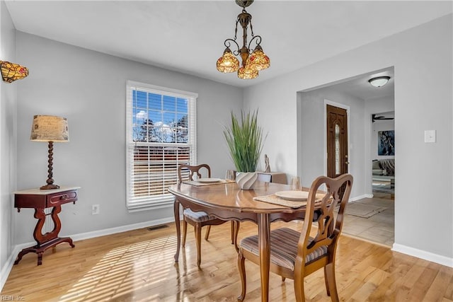 dining space with an inviting chandelier and light hardwood / wood-style flooring