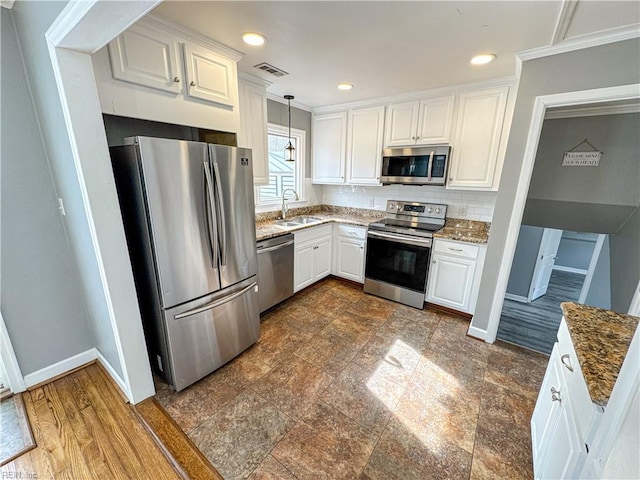 kitchen featuring sink, appliances with stainless steel finishes, pendant lighting, dark stone counters, and white cabinets