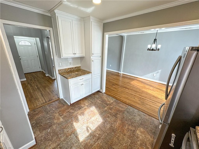 kitchen with white cabinetry, ornamental molding, and stainless steel refrigerator