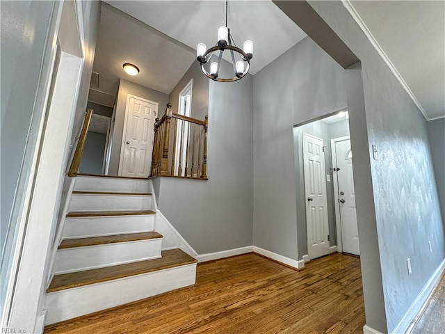 staircase featuring crown molding, hardwood / wood-style floors, and a notable chandelier