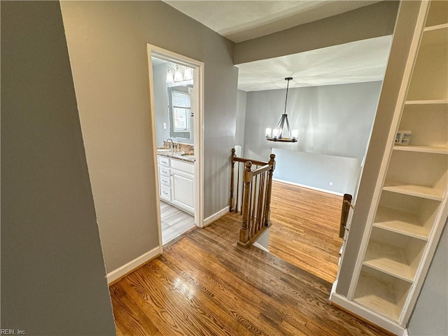 hallway featuring sink, hardwood / wood-style floors, and a notable chandelier