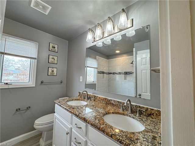 bathroom with vanity, toilet, and a tile shower