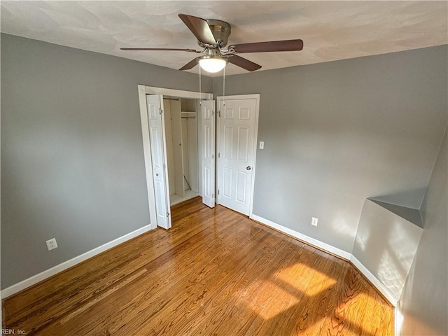 unfurnished bedroom with ceiling fan, wood-type flooring, and a closet