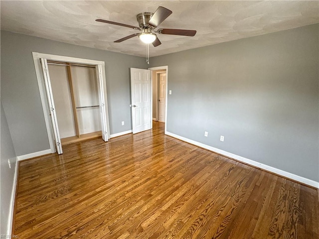 unfurnished bedroom featuring ceiling fan, hardwood / wood-style floors, and a closet