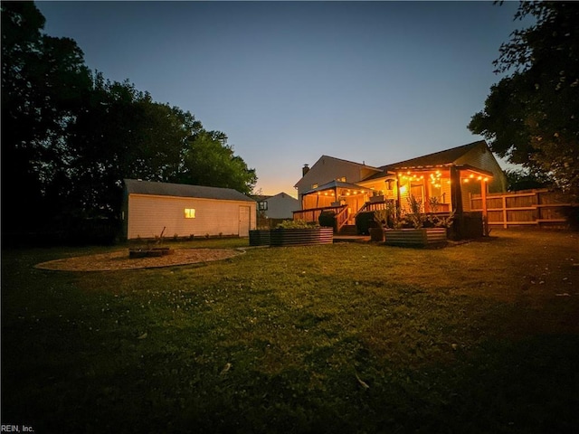 yard at dusk featuring a storage shed and a wooden deck