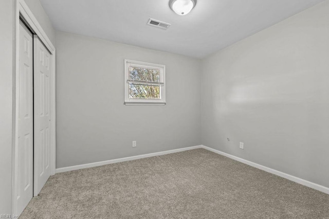 unfurnished bedroom with light colored carpet and a closet