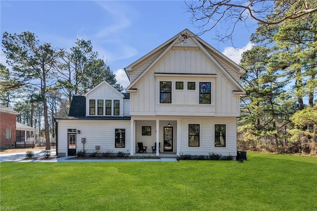 modern farmhouse style home featuring cooling unit, a front yard, and covered porch