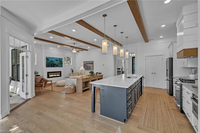 kitchen with white cabinetry, appliances with stainless steel finishes, hanging light fixtures, and a large island with sink