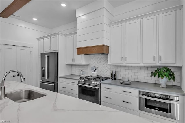 kitchen featuring light stone counters, sink, stainless steel appliances, and white cabinets