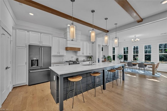 kitchen featuring appliances with stainless steel finishes, decorative light fixtures, a breakfast bar area, white cabinets, and a large island