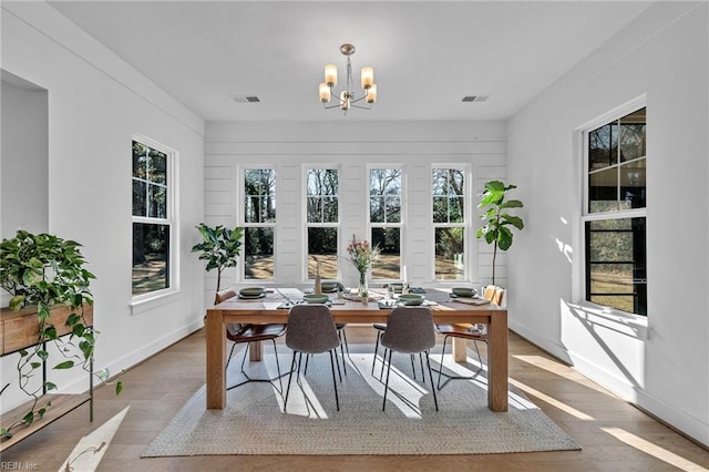 dining area with an inviting chandelier, light wood-type flooring, and a wealth of natural light