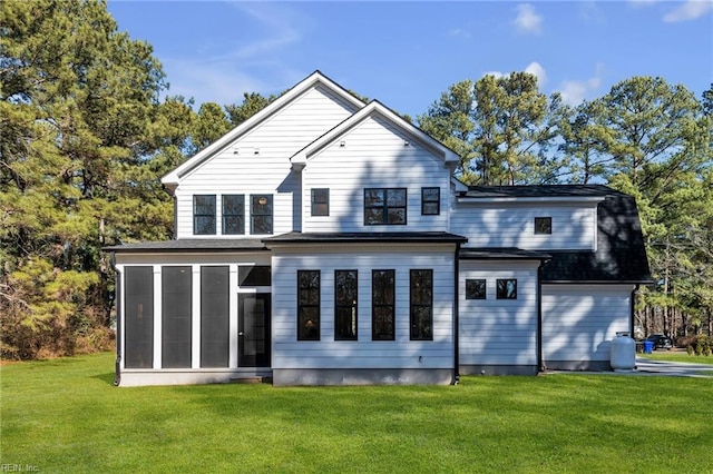 rear view of property featuring a sunroom and a lawn