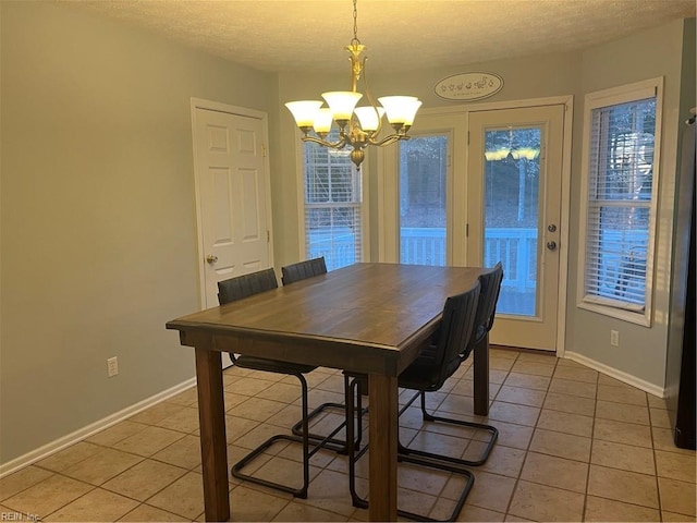 tiled dining space with a textured ceiling and a chandelier