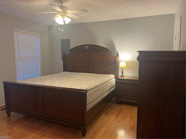 bedroom with ceiling fan, light hardwood / wood-style floors, and a textured ceiling