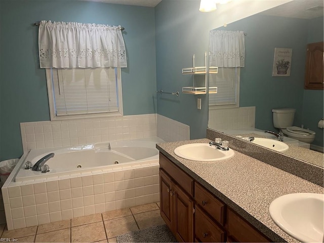 bathroom with tile patterned flooring, vanity, tiled tub, and toilet