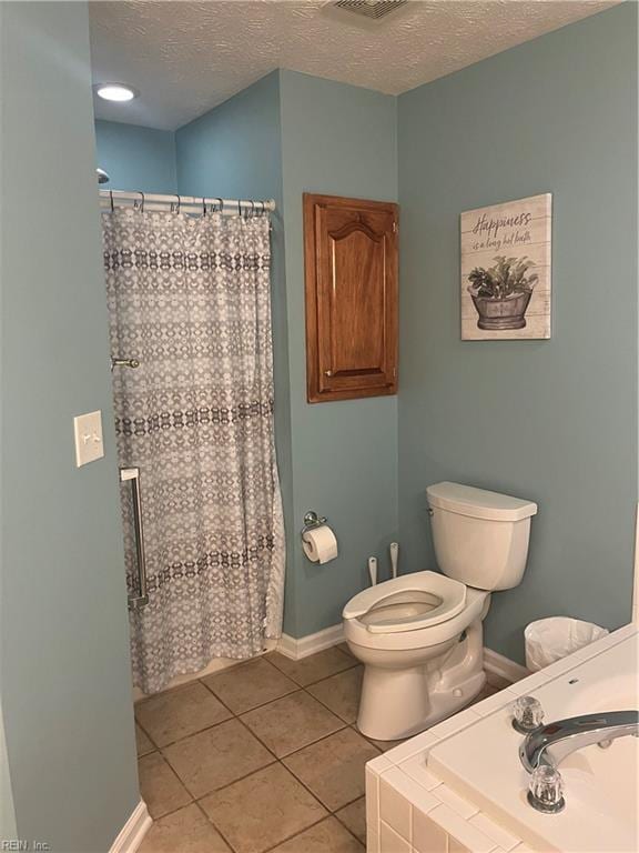 bathroom with tile patterned floors, toilet, curtained shower, and a textured ceiling