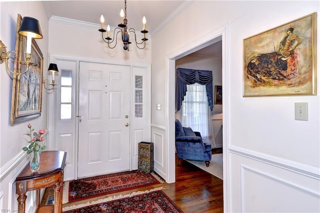 entryway with ornamental molding, dark wood-type flooring, and a chandelier