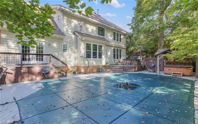 back of property with a swimming pool with hot tub