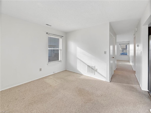 unfurnished room with light carpet and a textured ceiling