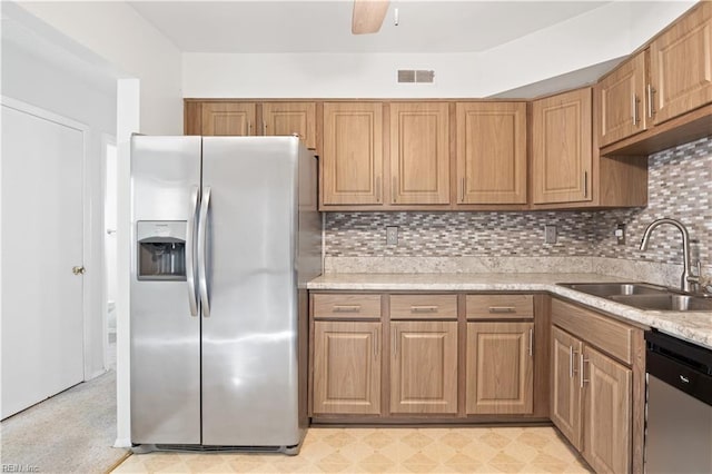 kitchen with light stone counters, stainless steel appliances, sink, and decorative backsplash