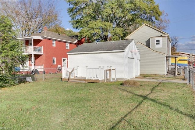 rear view of house featuring a garage, a yard, and an outdoor structure