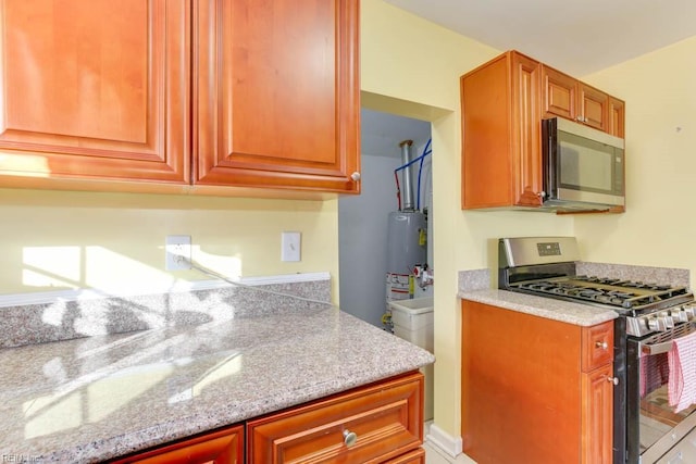 kitchen with gas water heater, appliances with stainless steel finishes, and light stone counters