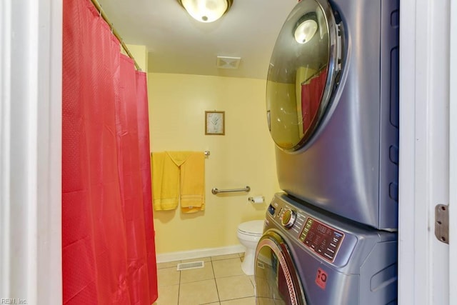 bathroom featuring tile patterned floors, toilet, and stacked washer / dryer