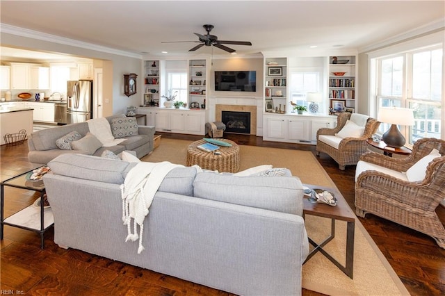 living room featuring sink, crown molding, dark wood-type flooring, built in features, and ceiling fan