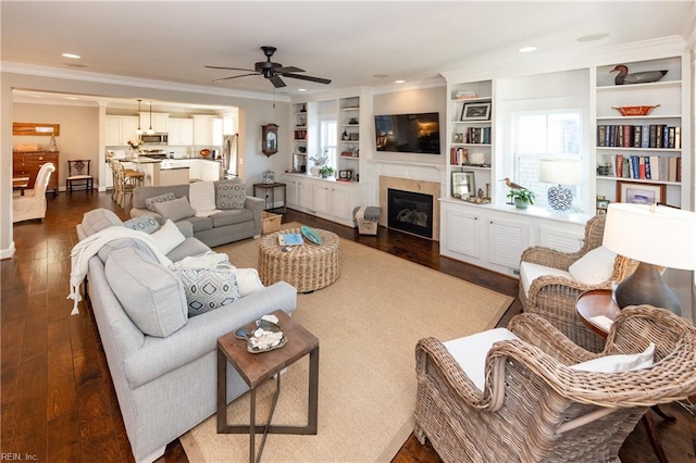 living room featuring dark wood-type flooring, ceiling fan, ornamental molding, and built in shelves