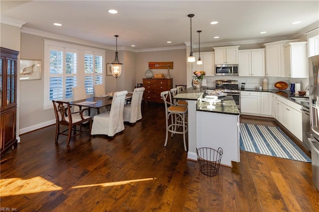 kitchen featuring decorative light fixtures, a center island, appliances with stainless steel finishes, dark stone counters, and white cabinets