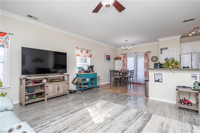 living room with light hardwood / wood-style flooring, ceiling fan with notable chandelier, plenty of natural light, and ornamental molding