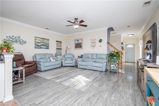 living room with crown molding, ceiling fan, and light wood-type flooring