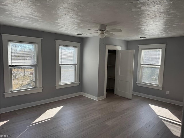 unfurnished bedroom featuring hardwood / wood-style flooring, a closet, multiple windows, and a textured ceiling