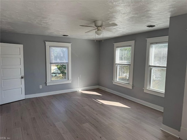 unfurnished room featuring ceiling fan, a healthy amount of sunlight, a textured ceiling, and light wood-type flooring