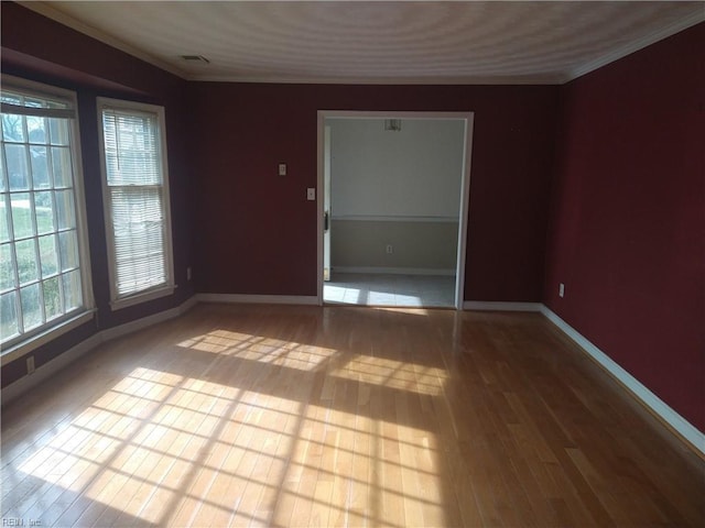 empty room with crown molding and light hardwood / wood-style flooring