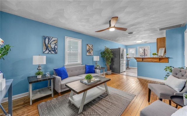 living room featuring a textured ceiling, light hardwood / wood-style floors, and ceiling fan