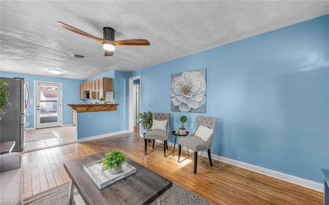 living room featuring a textured ceiling, ceiling fan, and light hardwood / wood-style flooring