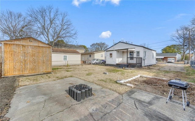 back of property featuring a storage unit, a patio area, and an outdoor fire pit