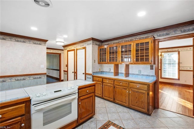 kitchen featuring crown molding, electric range, tile counters, and light tile patterned flooring