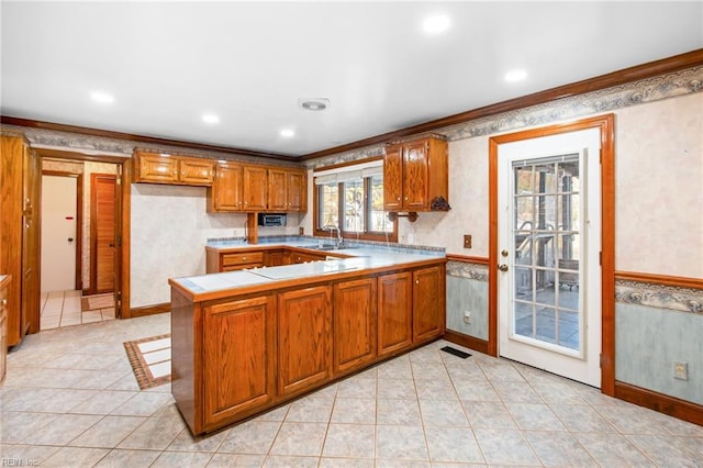 kitchen with light tile patterned flooring, sink, crown molding, and kitchen peninsula