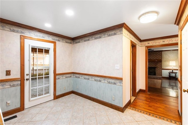 spare room with light tile patterned floors, crown molding, and a fireplace