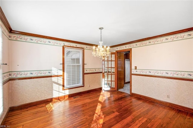 unfurnished dining area with hardwood / wood-style flooring, crown molding, and a chandelier