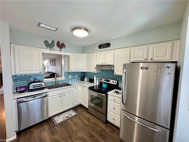 kitchen with appliances with stainless steel finishes, dark hardwood / wood-style floors, tasteful backsplash, white cabinetry, and sink